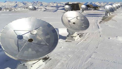 An array of telescopes on a snow-capped mountain.
